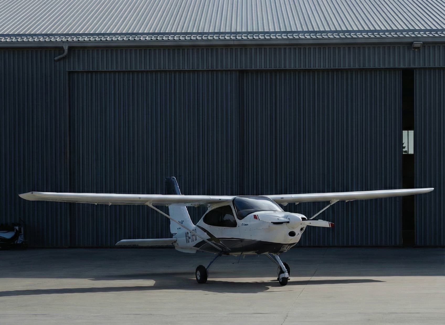 Avion léger devant un hangar d'aéroclub